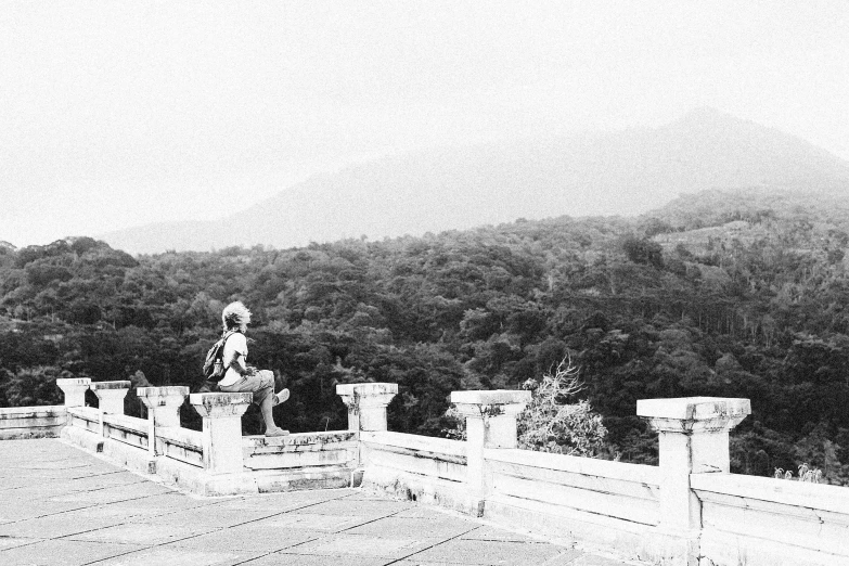 a black and white po shows a woman sitting on an old fashioned bridge