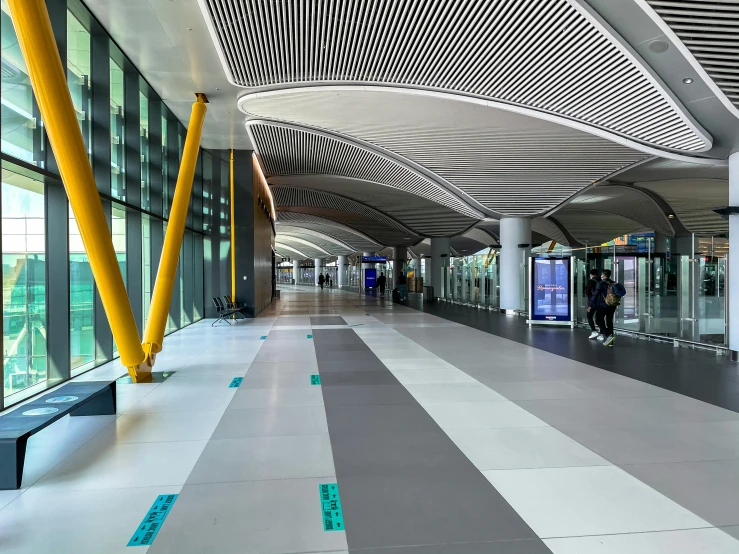 an empty airport with many glass doors and yellow poles