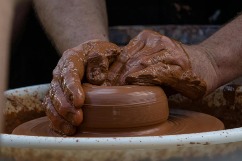 someone working on a clay pot on an potter's wheel