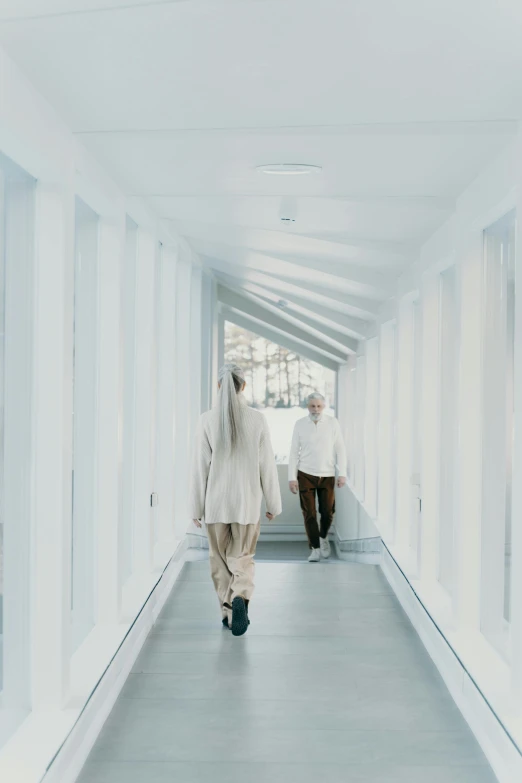 two women walking down a hallway that has white walls