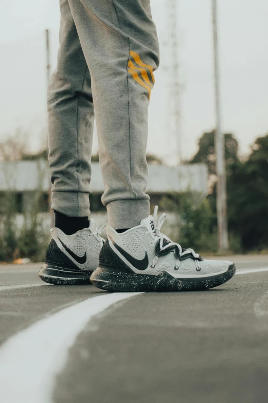 a person's feet and legs on the ground in sneakers