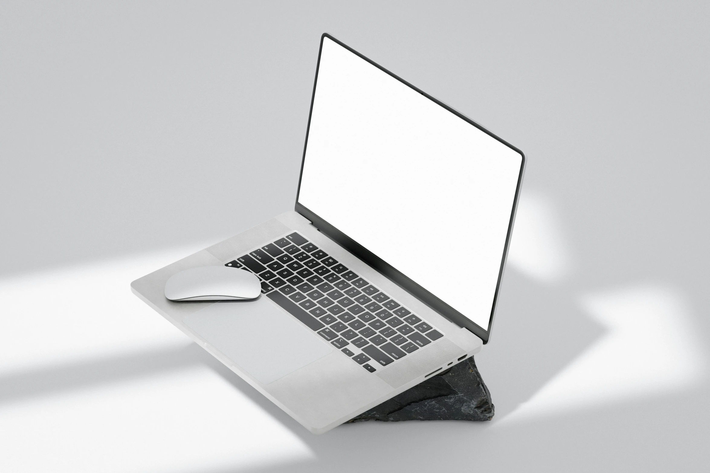 a laptop and mouse on a white surface