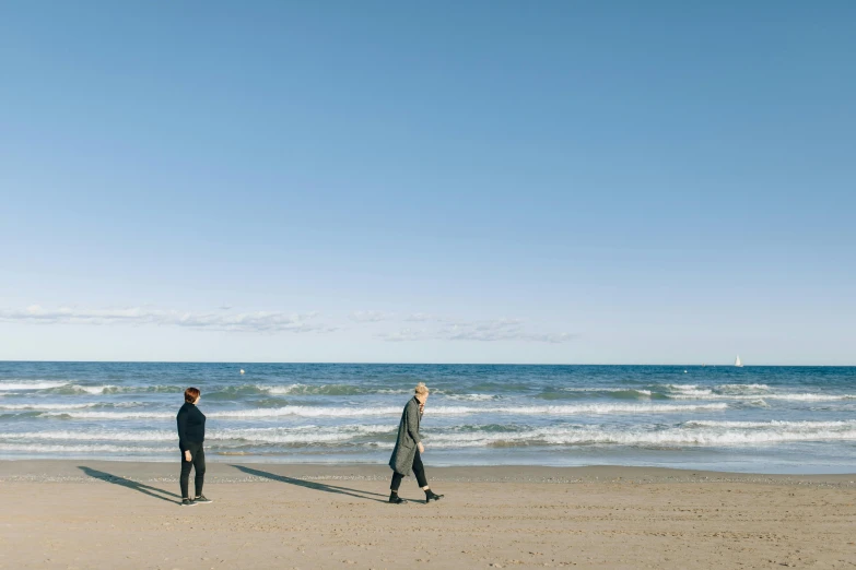 two people in black suits standing on the beach