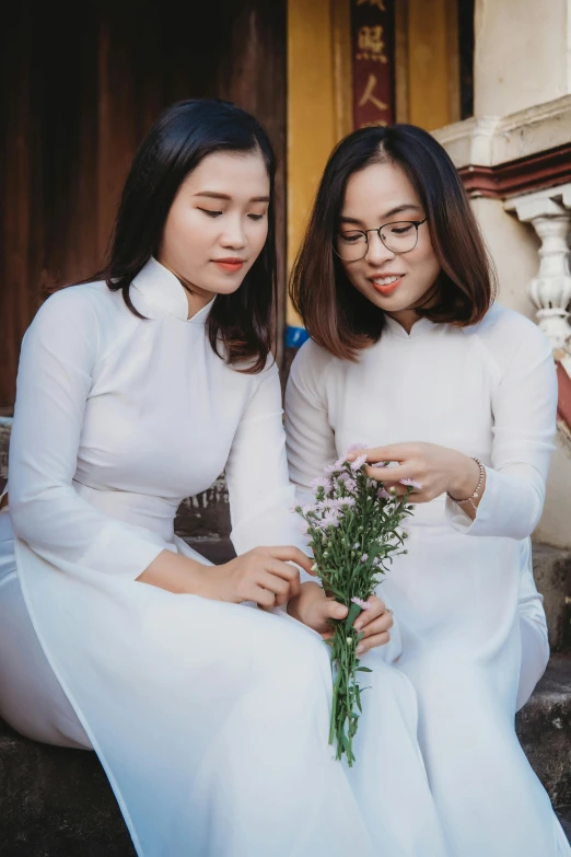 two beautiful young women sitting on the ground next to each other