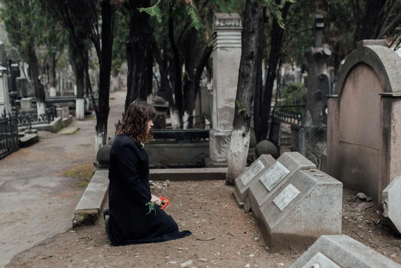 there is a woman kneeling at the grave yard