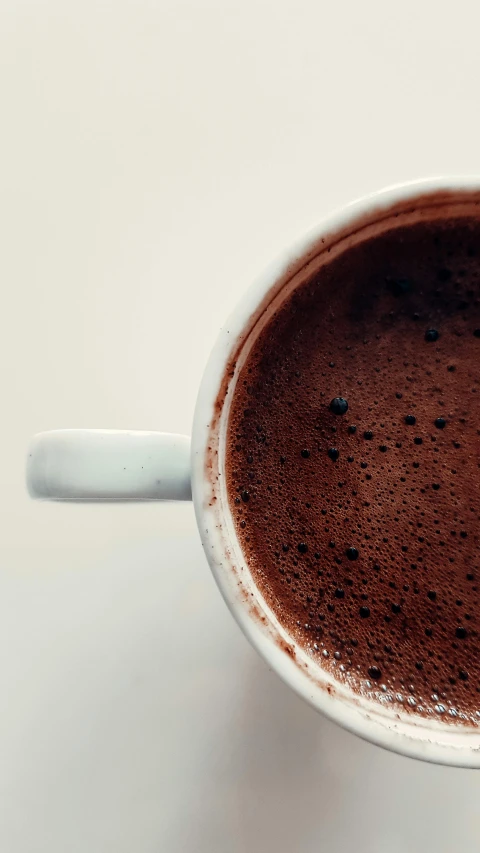 a white mug filled with  chocolate on top of a table