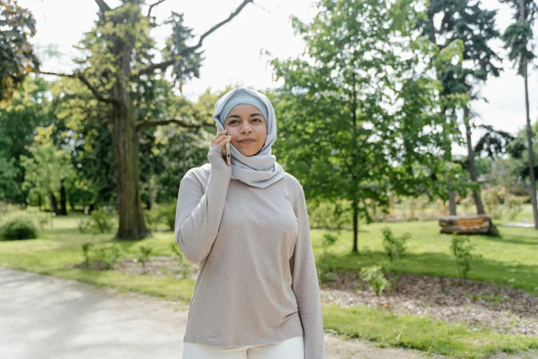 woman in headscarf with finger on mouth talking on cellphone