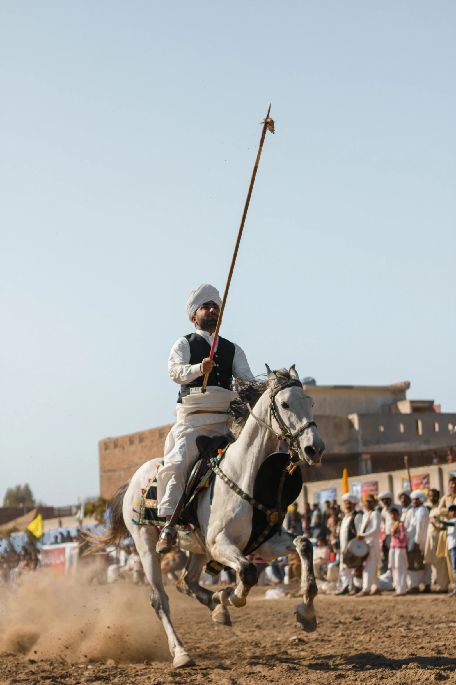 a man riding on the back of a white horse next to a crowd