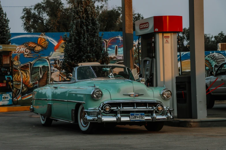 a classic car is parked next to an old gas pump