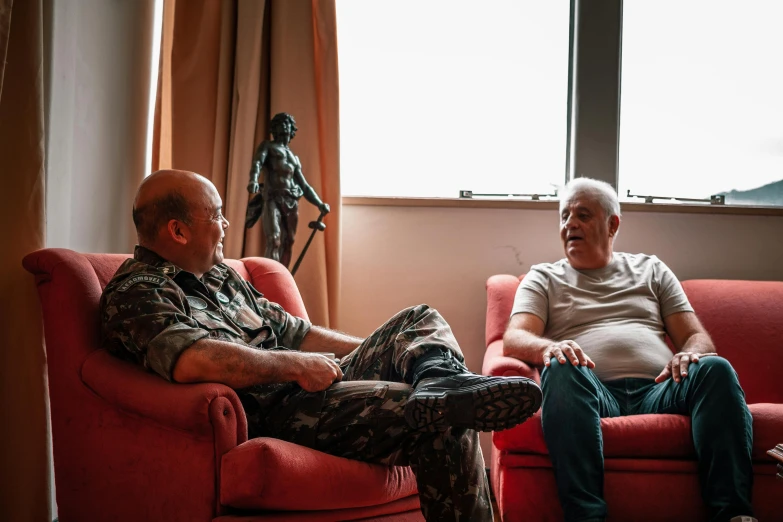 two men sitting on chairs facing each other