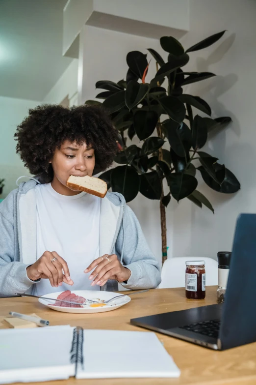 a woman is sitting at a table while eating a sandwich