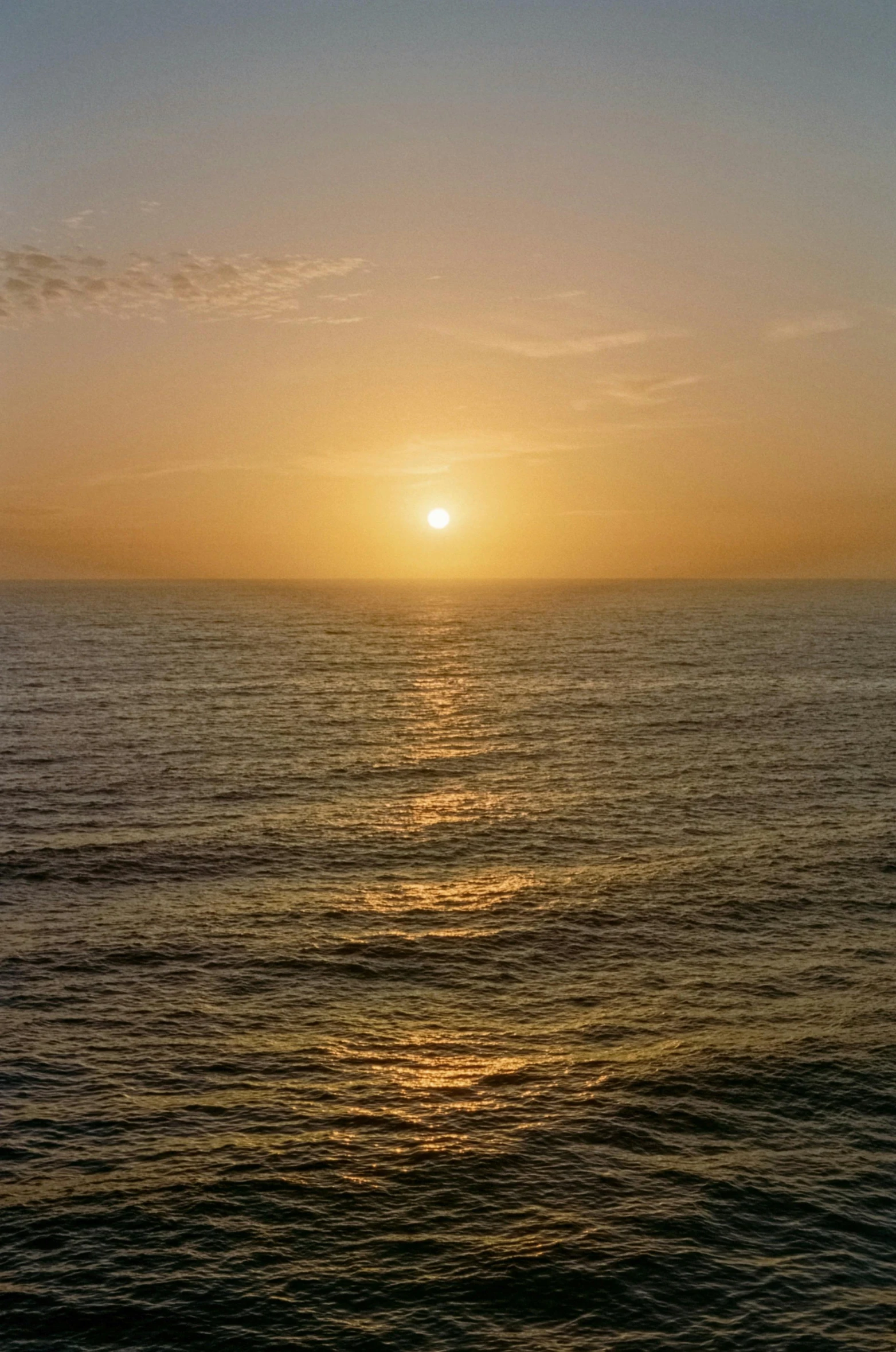 a sunset over a body of water with a boat on the water