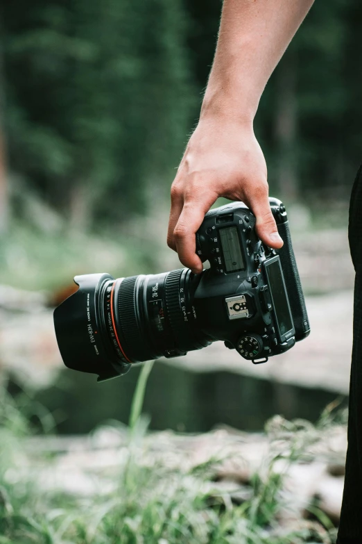 a person's hand holding a camera lens and looking through the lens