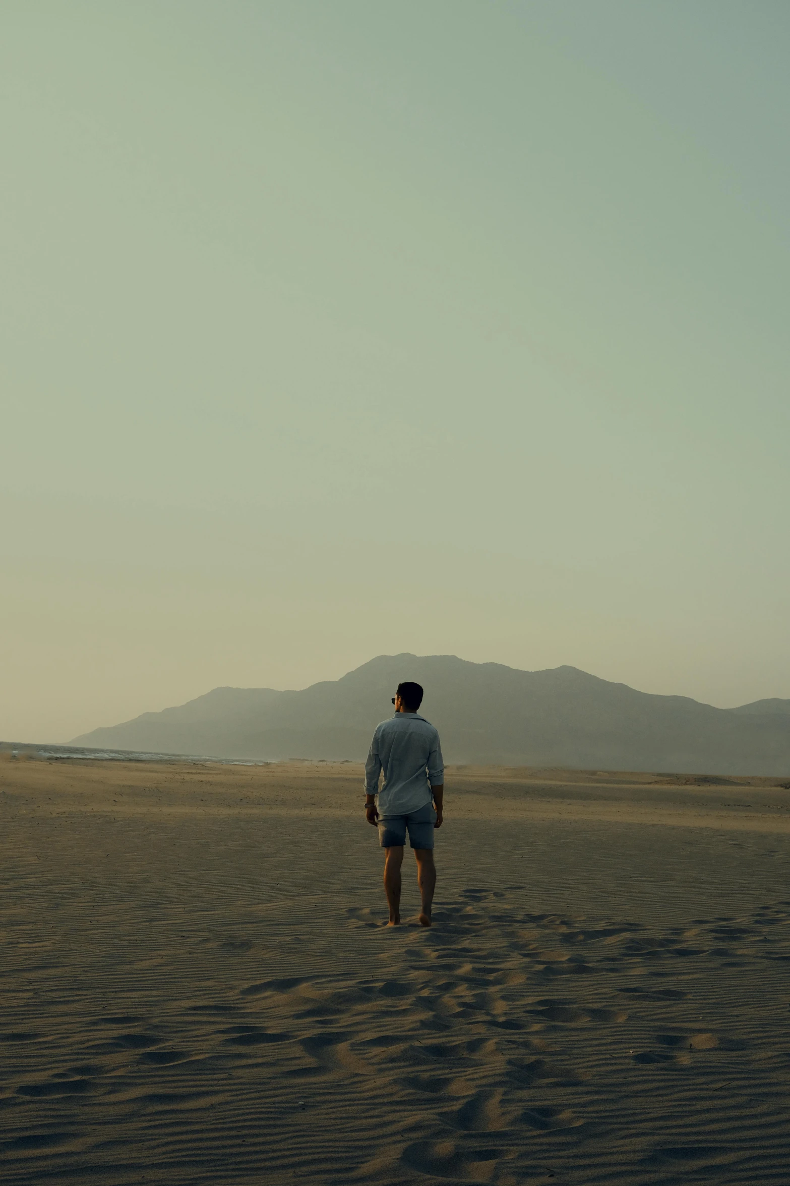 man looking out to distant mountains in an open desert