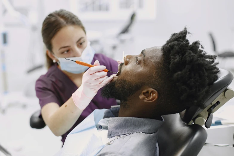 woman sitting in dentist chair while man eats food with fork