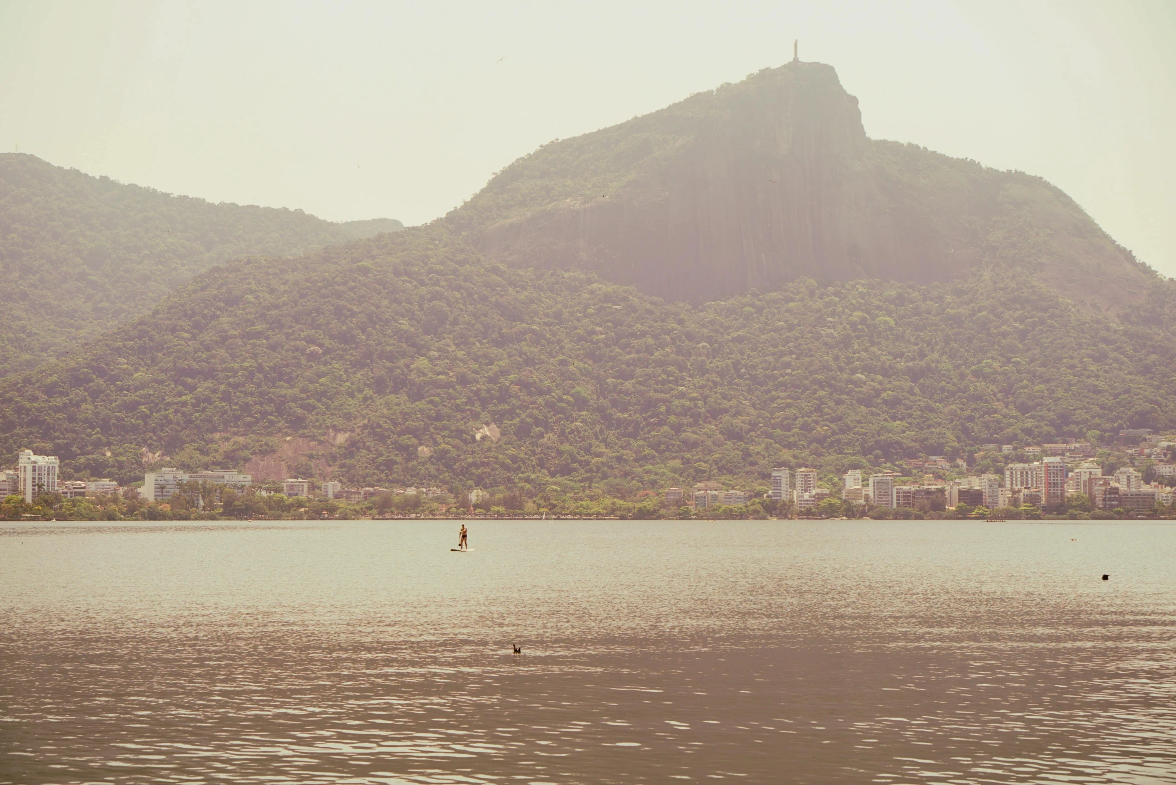 a view of a mountain side with a man rowing in the water