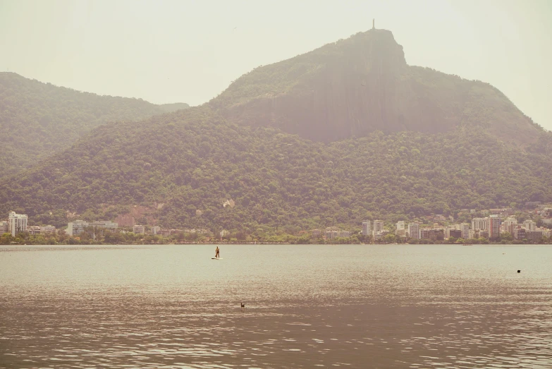 a view of a mountain side with a man rowing in the water