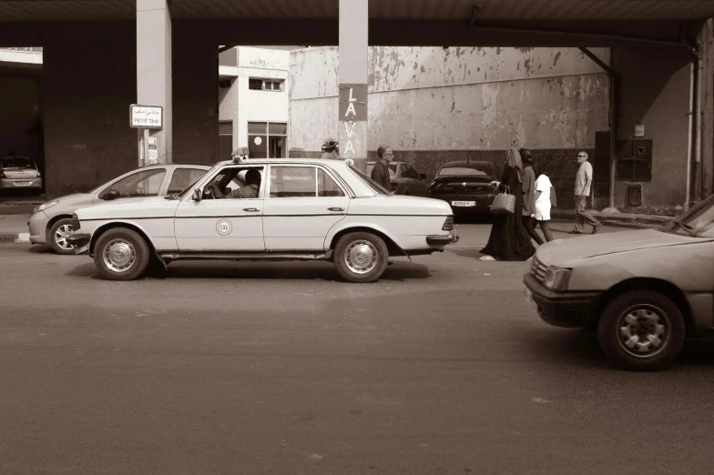 a woman walks by an old white car