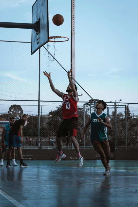 a group of young men playing basketball on top of a court