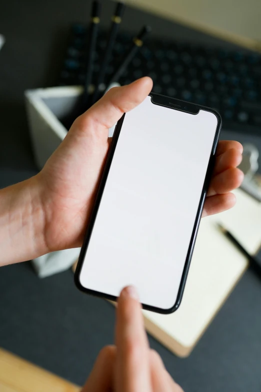 someone holding up their iphone in front of their laptop