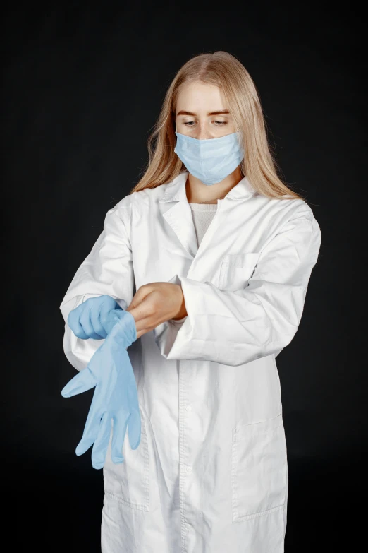 a woman in white coat with a medical mask and blue gloves