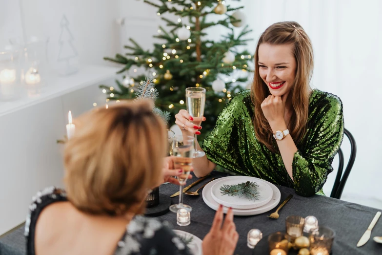 two women in a restaurant have a christmas meal and drink champagne