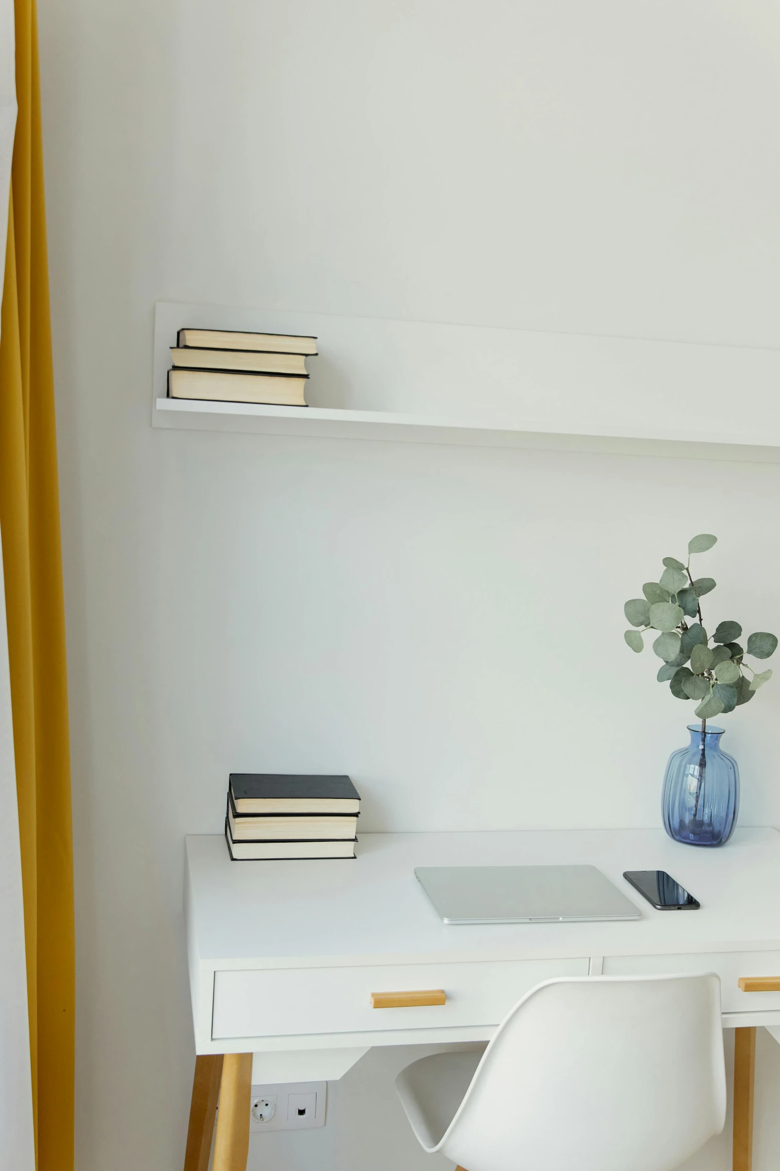 a white desk and shelf with two books