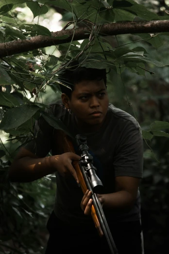 a young man holding a rifle in front of a nch