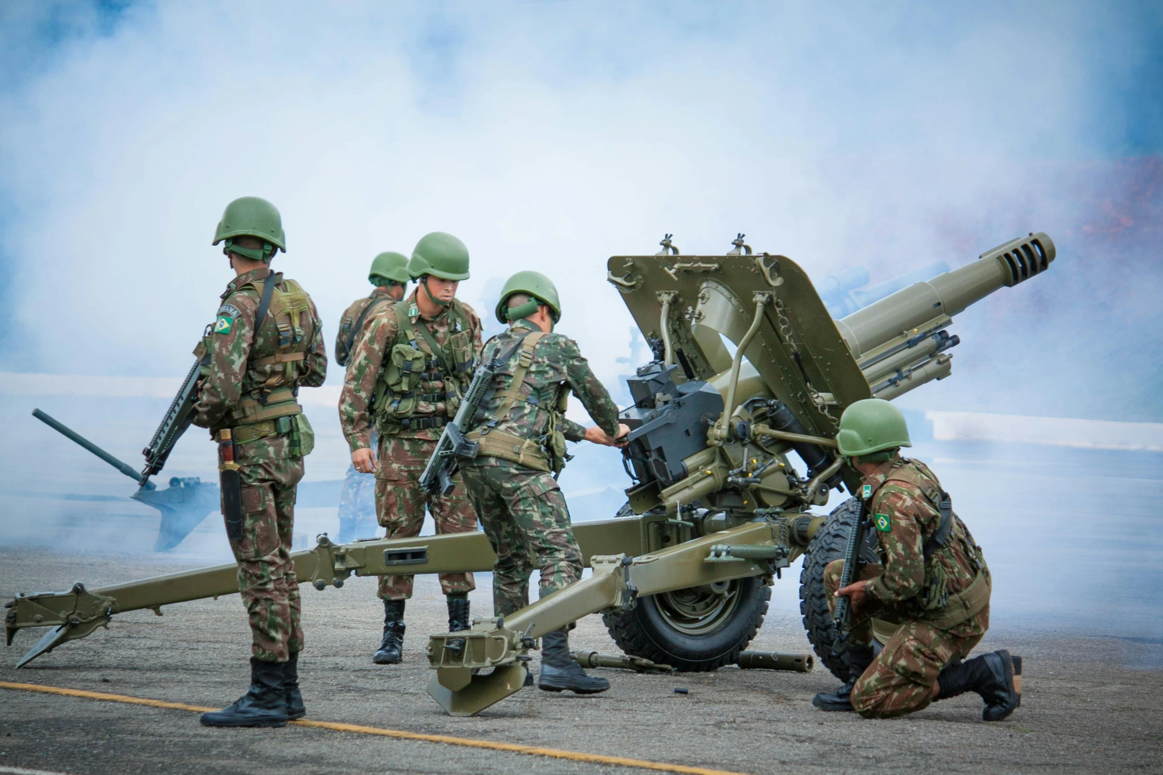 three men stand beside a very large gun and tank