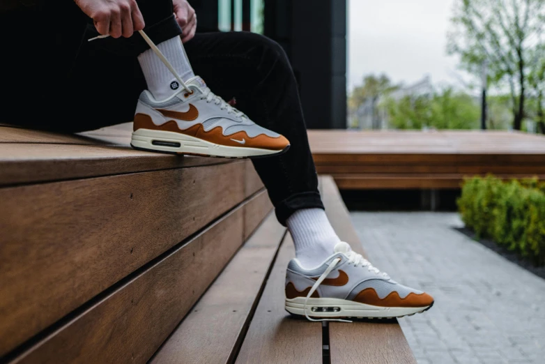 a person wearing brown and white shoes sitting on a bench