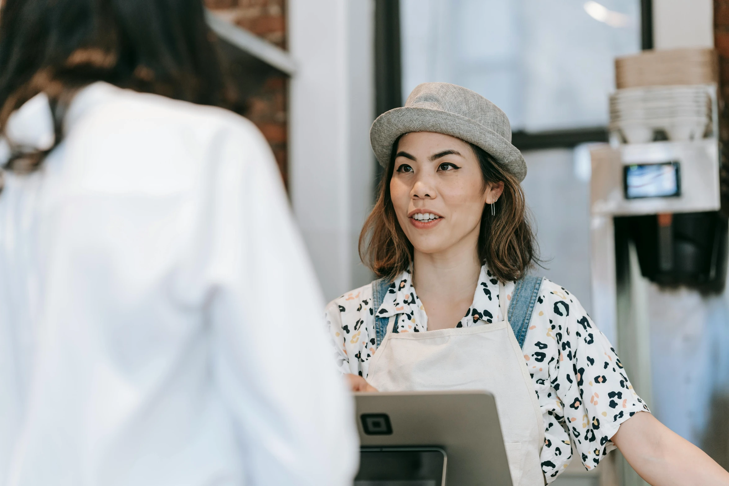 a woman standing in a counter area with a person behind her