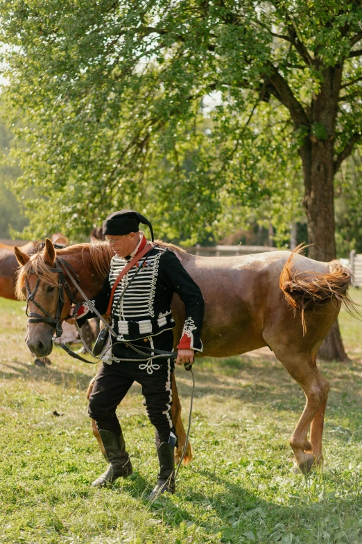 a man is holding the bridle of his horse while standing in a field