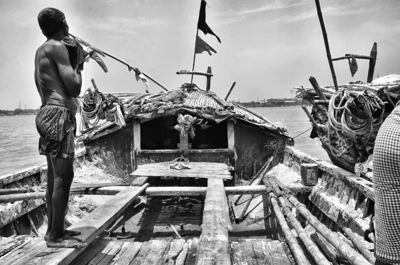 a man standing in the back of a wooden boat