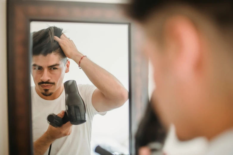 man standing in front of a mirror while straightening his hair