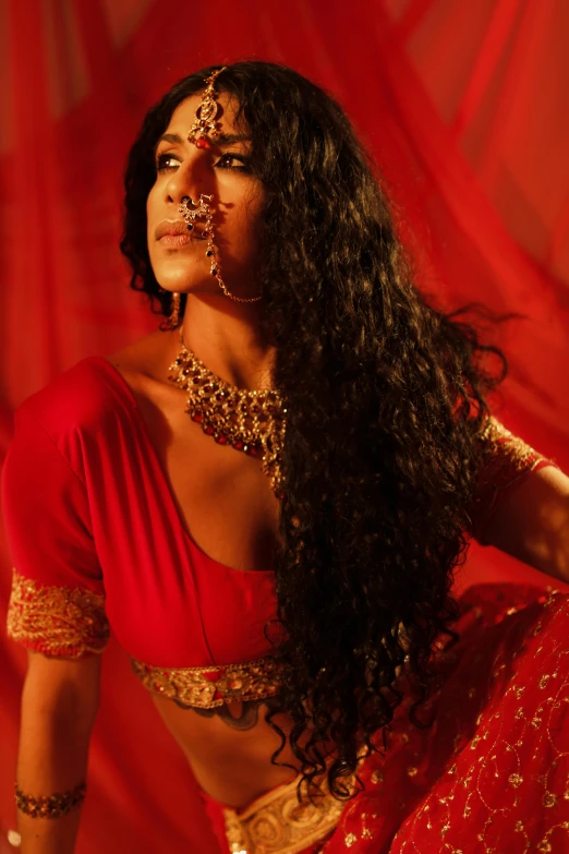 a woman in red with a gold necklace and gold jewelry