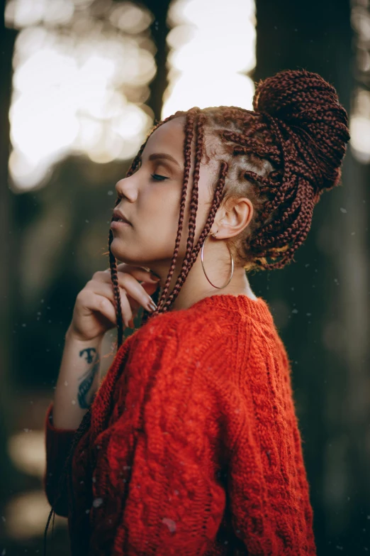 woman in orange sweater with hand in mouth outdoors