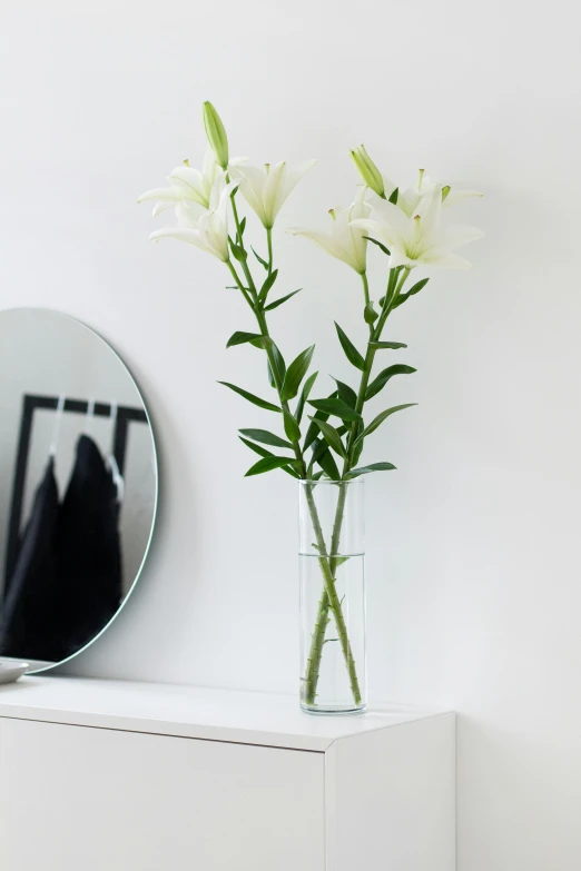 a white vase on a shelf and a round mirror