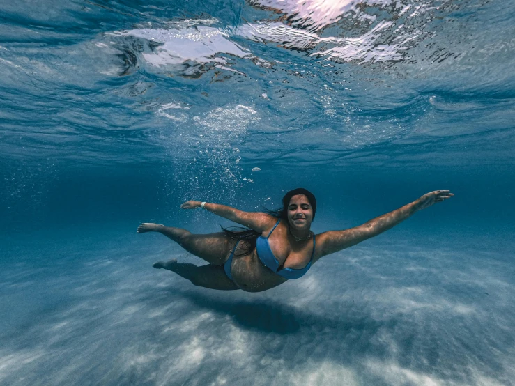 a woman swims under water in an ocean