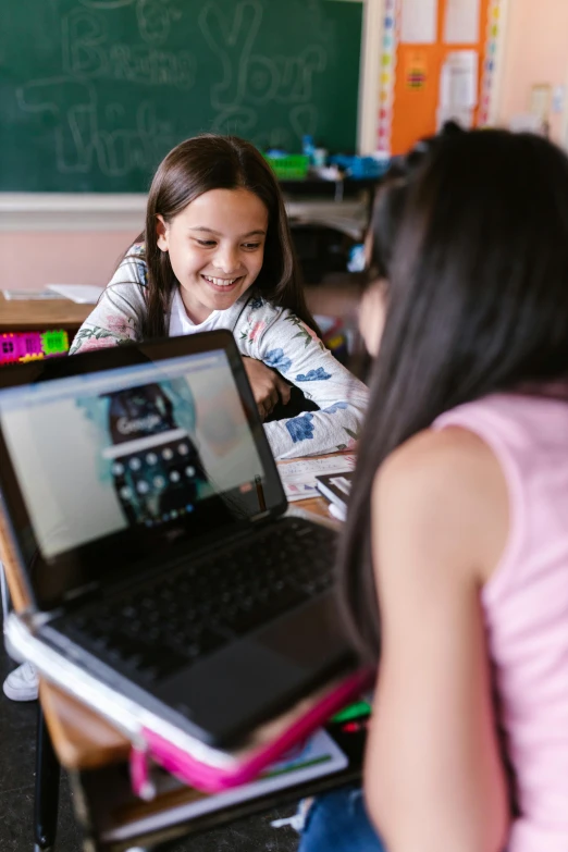 there are two girls that are at a laptop