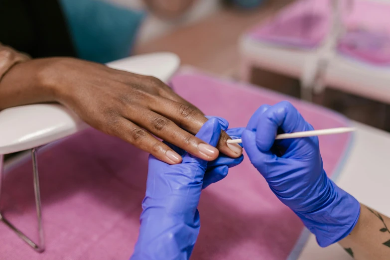 a woman gets her nails painted with purple