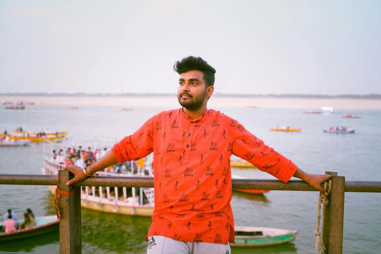 man in red shirt standing in front of a bridge with boats and people