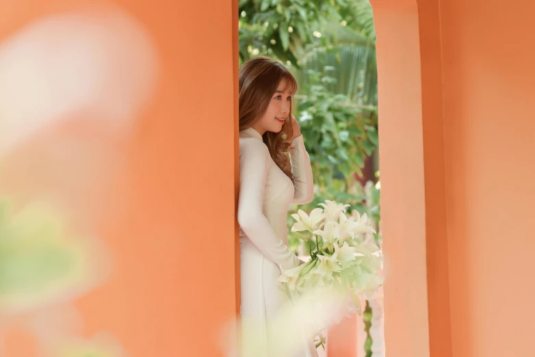 a beautiful woman standing near an orange wall