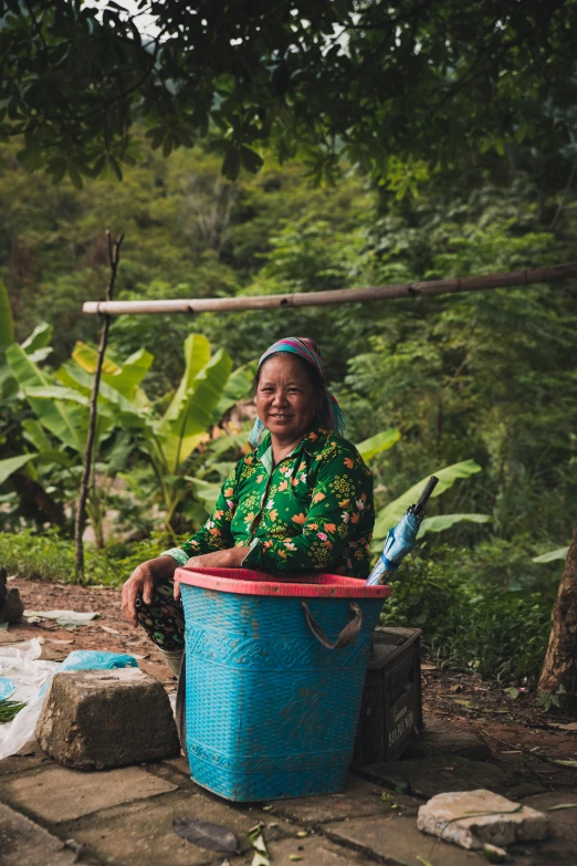 a woman sitting next to a blue tub filled with water