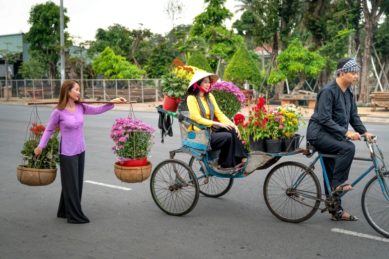 a woman riding on a bike and holding flower pot