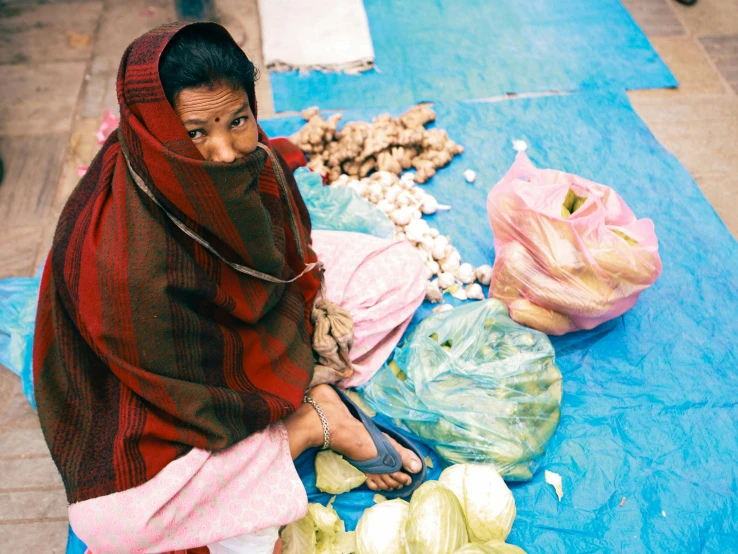 woman sitting on blanket near fruits and vegetables