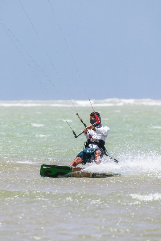 a kite boarder in the ocean with his skiis