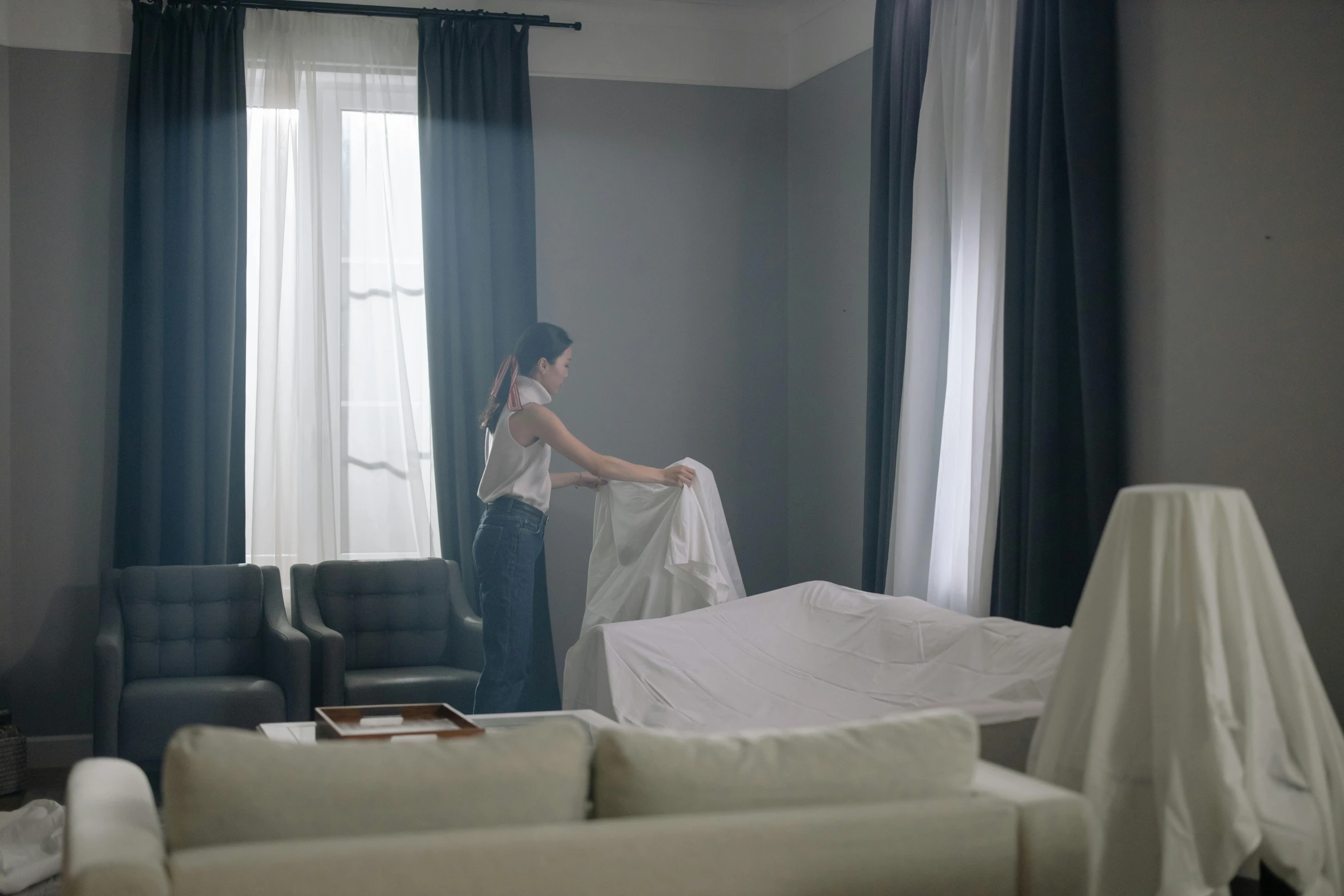 a woman in a living room, moving furniture from the house