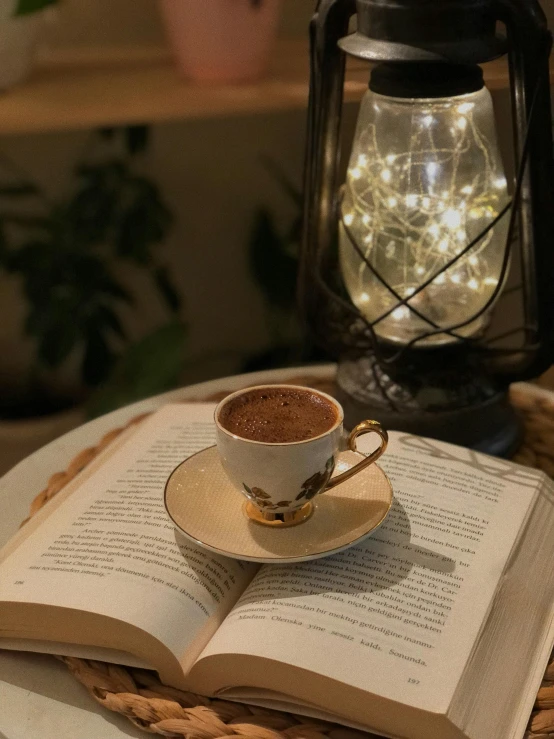 coffee cup with saucer and spoon sits in front of an open book