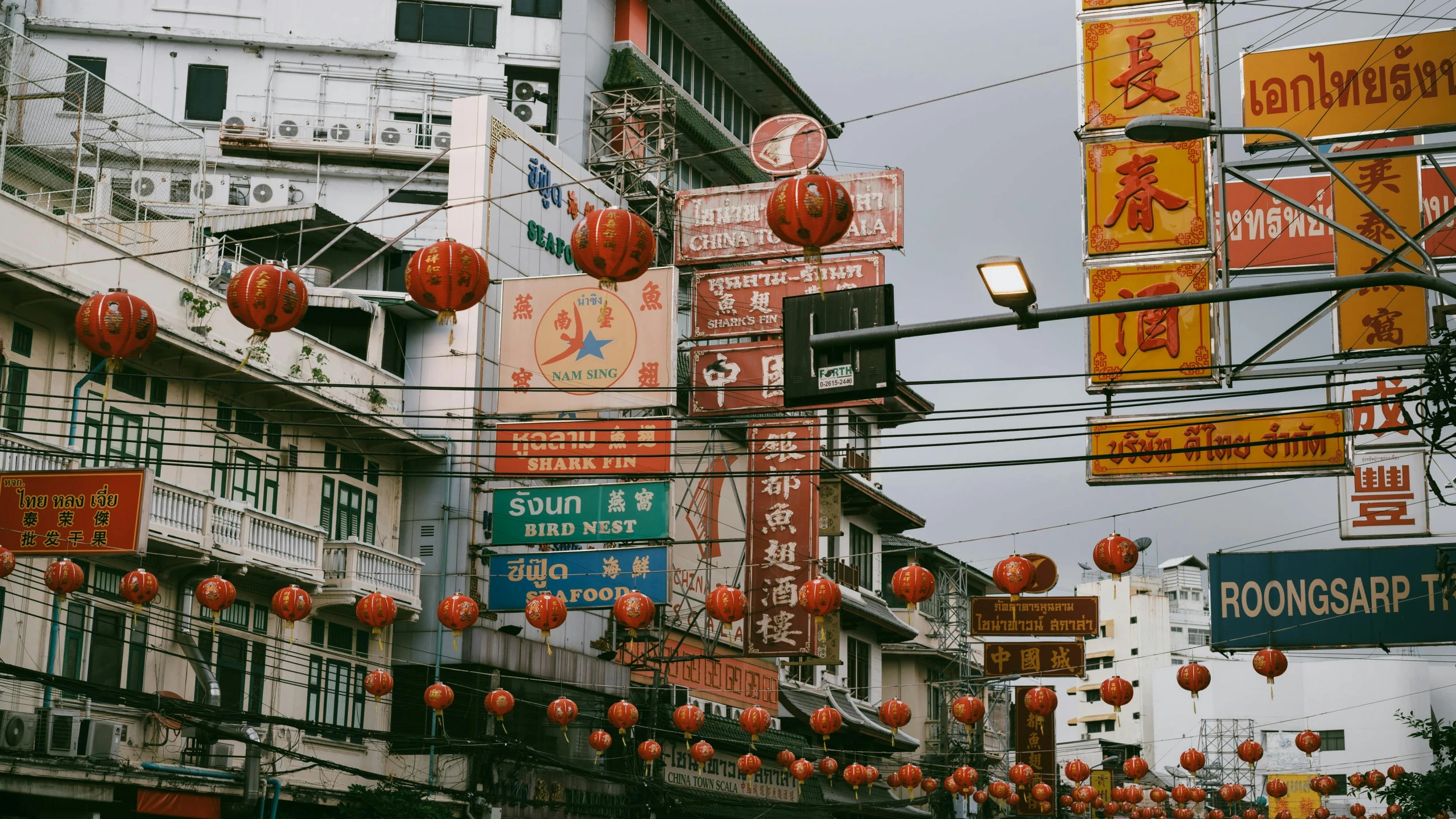 several red lanterns hung over an area with multiple buildings