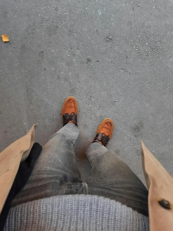 legs and feet with orange shoes stand with brown paper bags